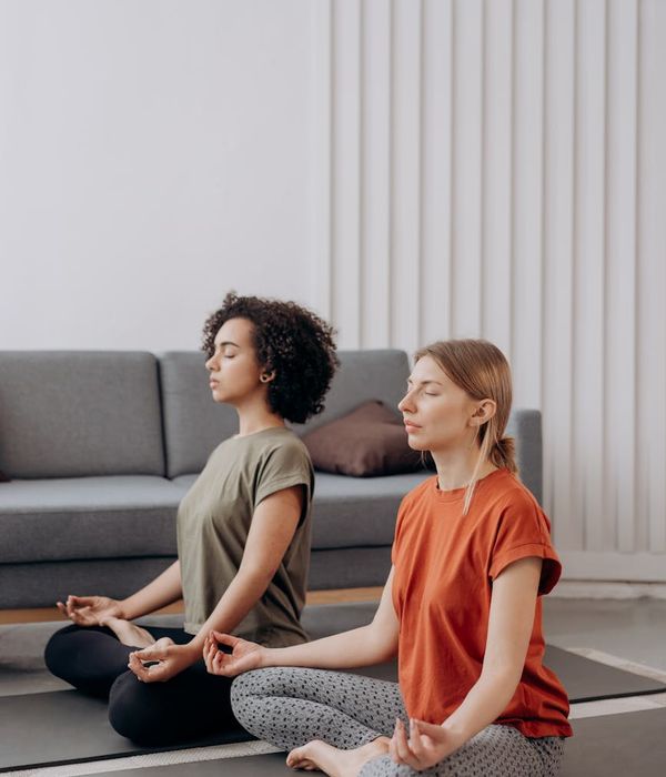 Woman in a peaceful yoga pose in a bright, minimalist room.